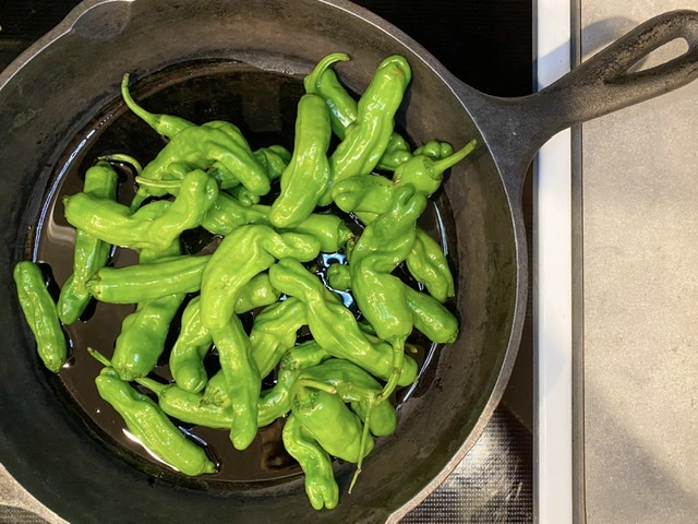 shishito peppers uncooked in an oiled cast iron skillet