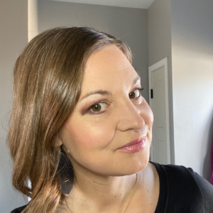 woman in a grey room with a black shirt and Curley hair