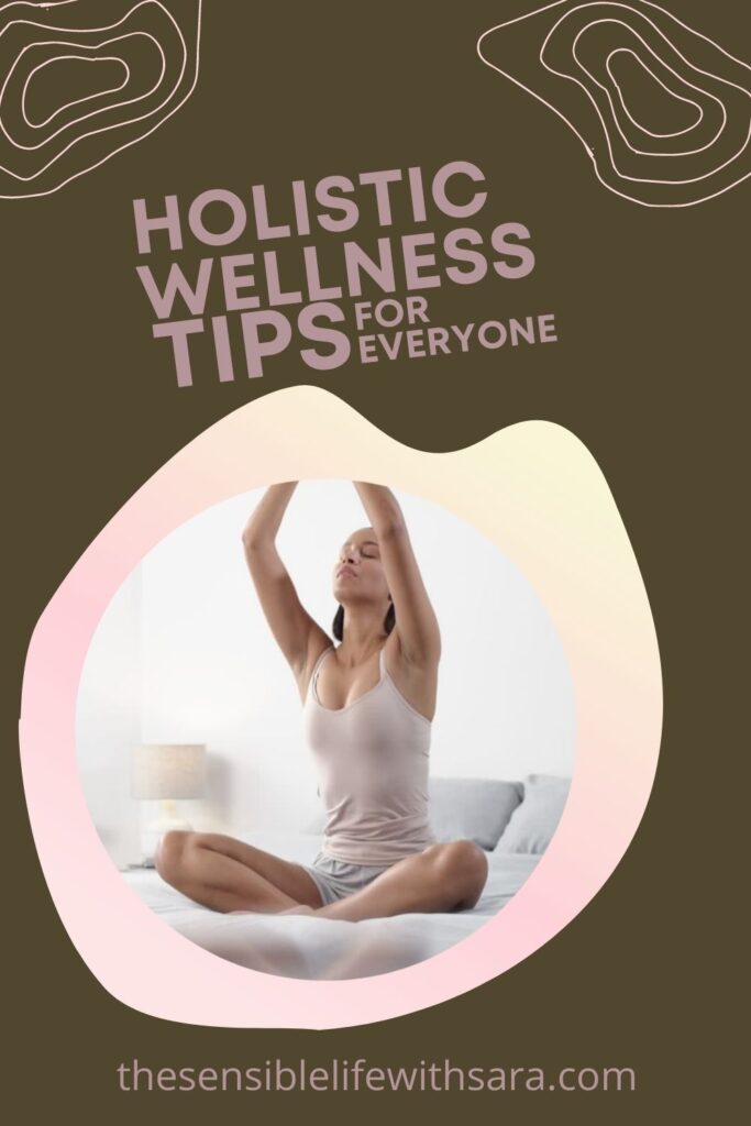 woman sitting cross legged on a bed with her eyes closed and her arms stretched above her head for wellness