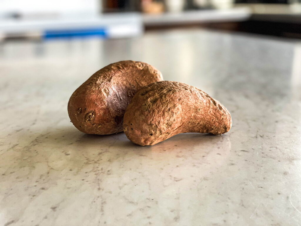 two sweet potatoes sitting on a white counter