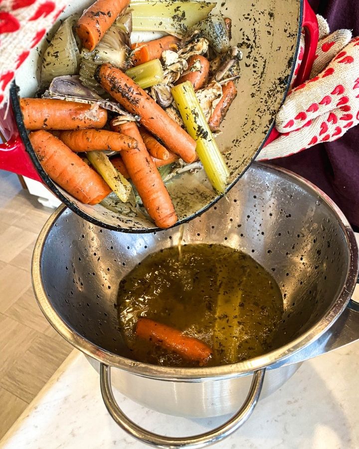 nourishing bone broth being strained through a colander