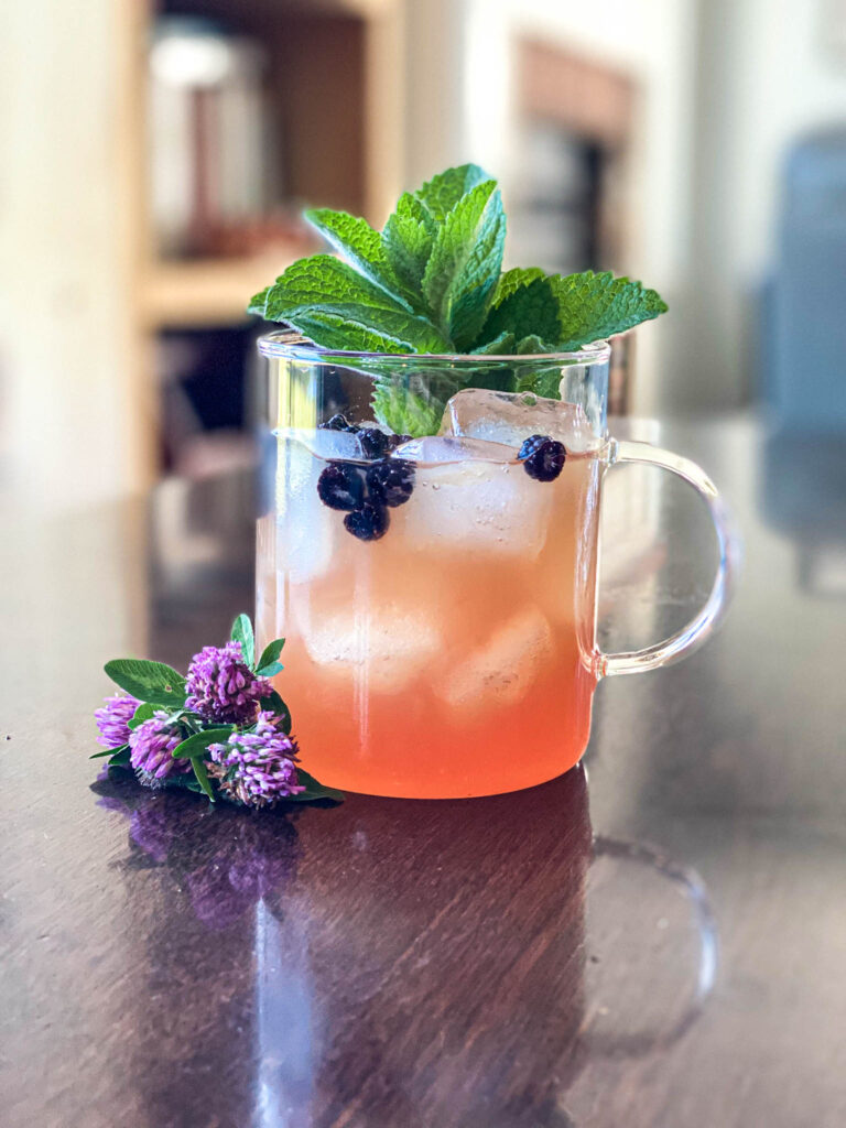 clear mug filled with foraged red clover lemonade on a wooden table