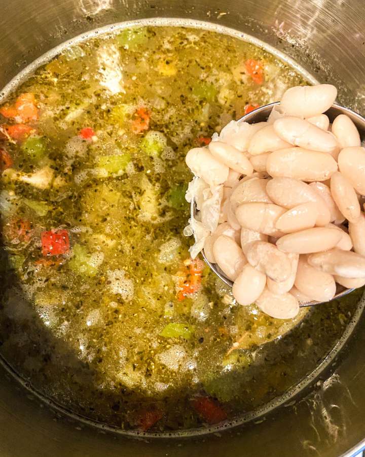 beans in a measuring cup held over a bowl of turkey chili