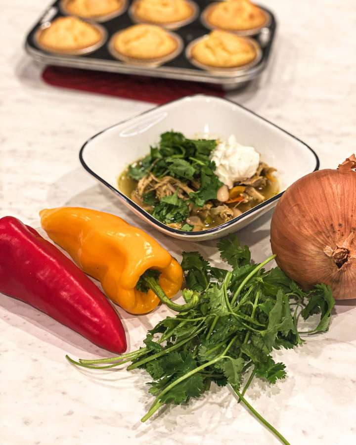 bowl of turkey and white bean chili verde next to cornbread muffins