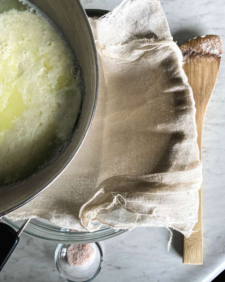 pouring ricotta cheese and whey into a cheesecloth