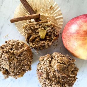 sourdough apple spice muffins sitting on a white counter next to an apple