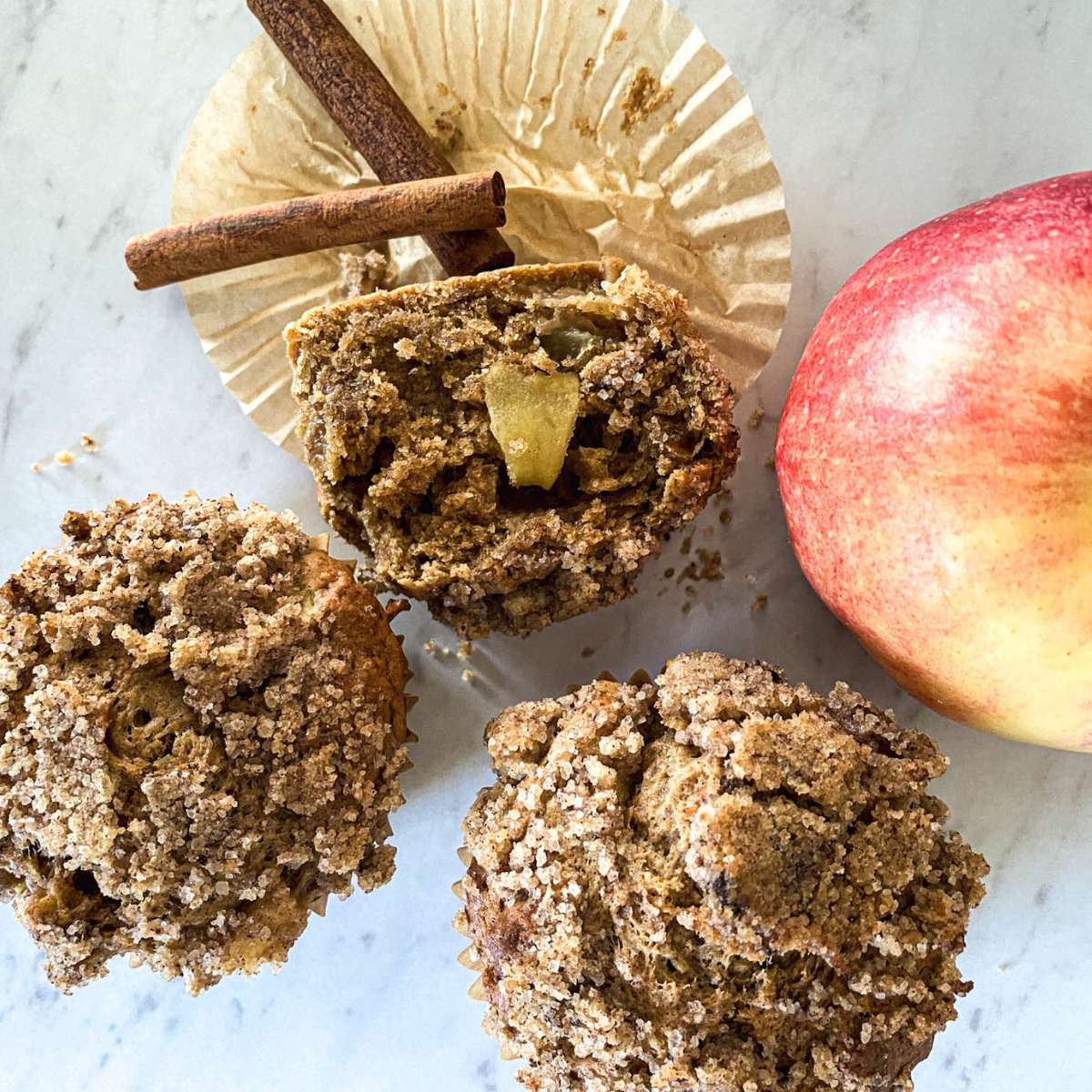 sourdough apple spice muffins sitting on a white counter next to an apple