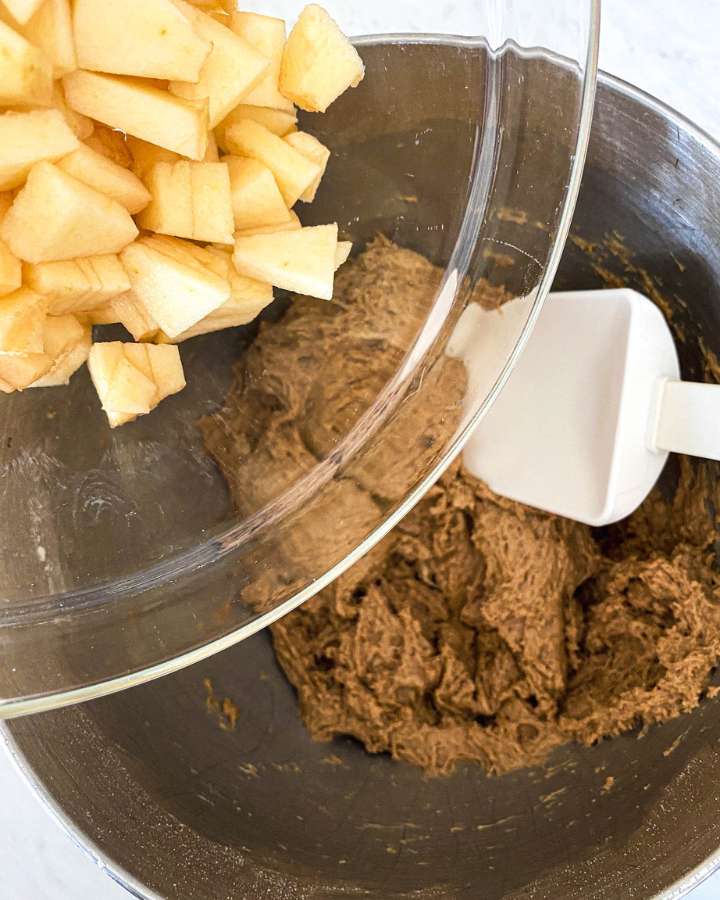 diced apples being poured into muffin batter