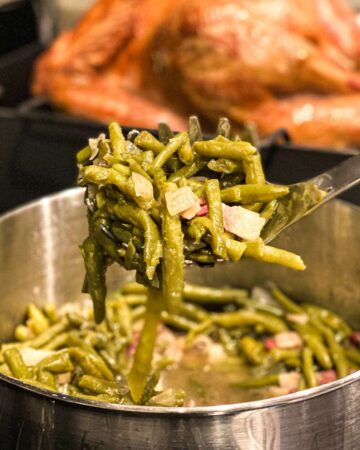 green beans on a serving spoon held in front of a turkey