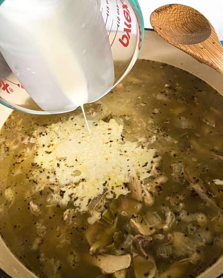 cream being poured into a pot of chicken chili