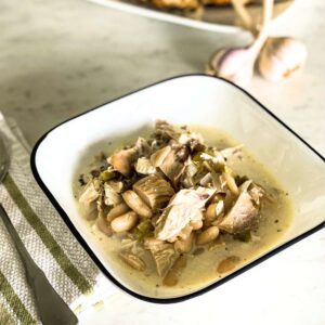 bowl of chicken chili on a white counter next to garlic and bread