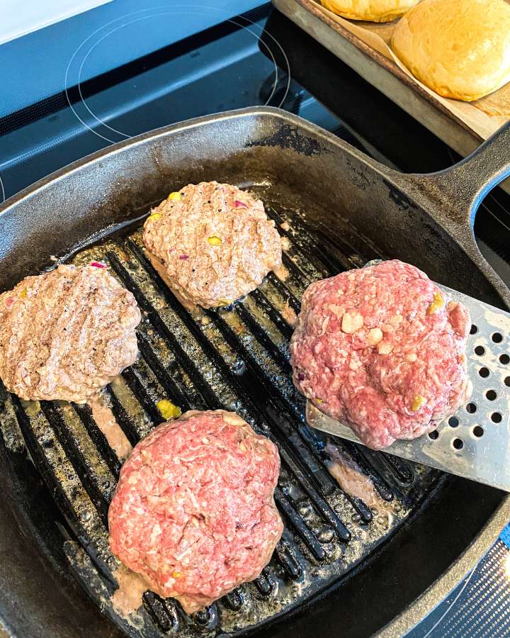 apple cheddar beef burger patties on a cast iron griddle