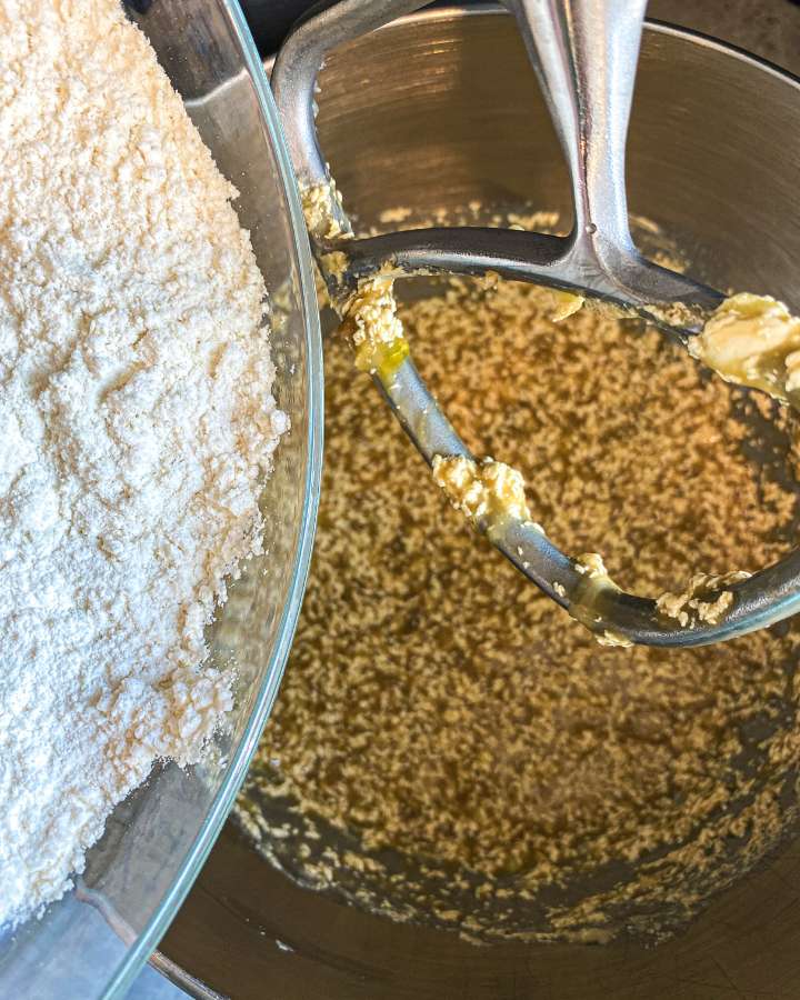 banana muffin batter in a stainless bowl with flour being poured into it